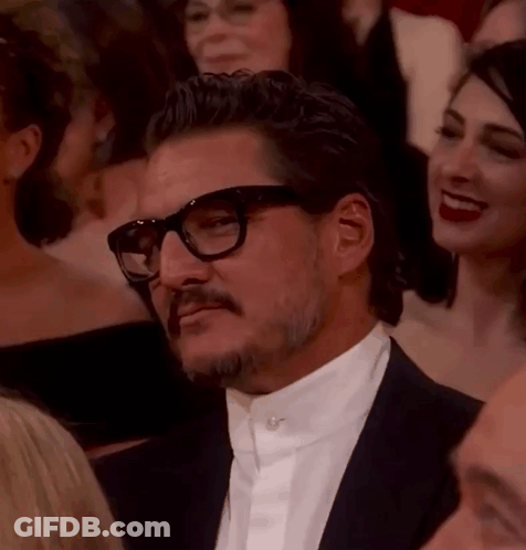 A Man With Glasses And A Mustache Is Sitting In A Crowd Of People . GIF
