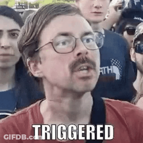 A Man With Glasses And A Mustache Is Standing In A Crowd Of People And Making A Funny Face . GIF