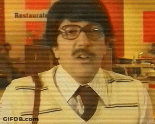 A Man With Glasses And A Mustache Is Standing In Front Of A Sign That Says Restaurante GIF