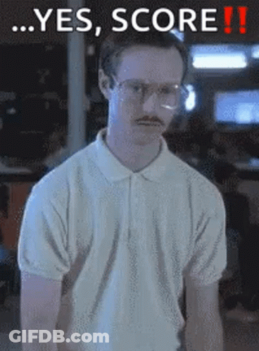 A Man With Glasses And A Mustache Is Standing In Front Of A Sign That Says Yes Score GIF