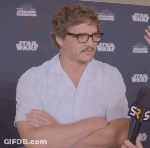 A Man With Glasses And A Mustache Stands In Front Of A Star Wars Sign GIF
