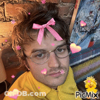 A Man With Glasses And A Pink Bow In His Hair Is Surrounded By Hearts And Stars GIF