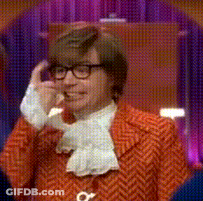 A Man With Glasses And A Red Jacket Is Talking On A Phone GIF