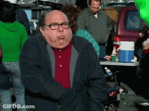 A Man With Glasses And A Red Shirt Is Standing In Front Of A Table With A Cooler On It . GIF