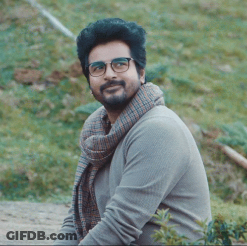 A Man With Glasses And A Scarf Around His Neck Smiles For The Camera GIF