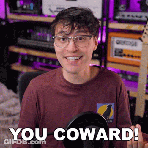 A Man With Glasses And A Shirt That Says You Coward GIF