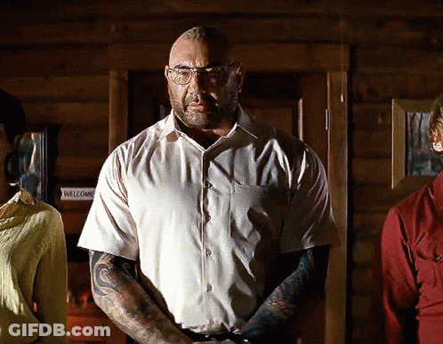 A Man With Glasses And A Tattoo On His Arm Stands In Front Of A Door That Says Welcome GIF