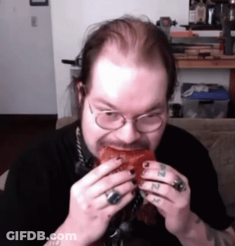 A Man With Glasses Is Eating A Piece Of Meat . GIF