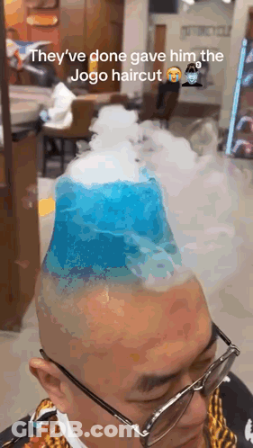 A Man With Glasses Is Getting A Haircut That Looks Like A Mountain With Smoke Coming Out Of It . GIF