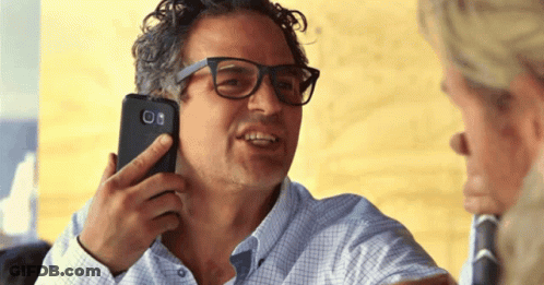 A Man With Glasses Is Holding A Cell Phone To His Ear GIF