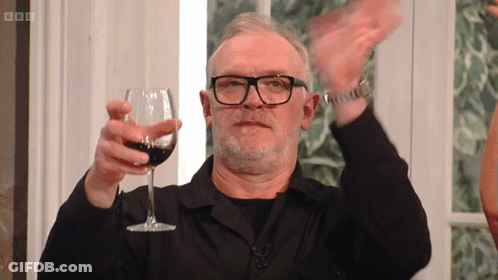 A Man With Glasses Is Holding A Glass Of Wine In His Hand GIF