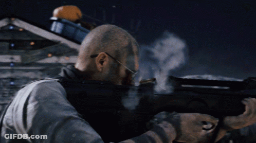 A Man With Glasses Is Holding A Gun And Shooting GIF