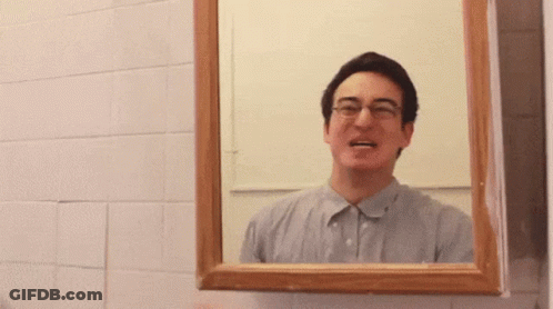A Man With Glasses Is Looking At Himself In A Bathroom Mirror GIF