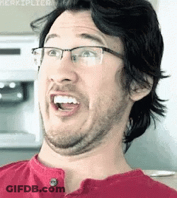 A Man With Glasses Is Making A Funny Face With His Mouth Open . GIF