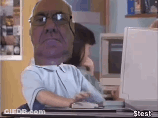 A Man With Glasses Is Sitting At A Desk With A Computer . GIF