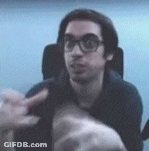 A Man With Glasses Is Sitting In A Chair And Pointing At Something GIF