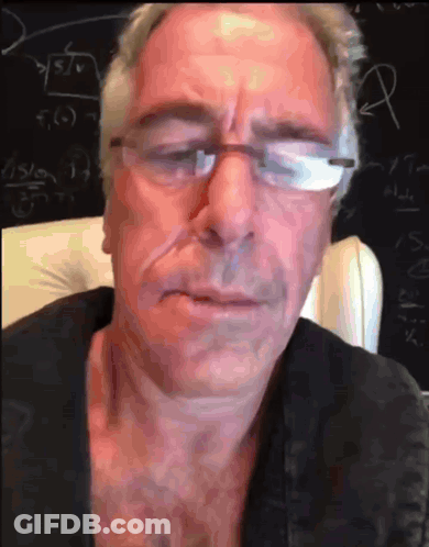 A Man With Glasses Is Sitting In Front Of A Blackboard GIF