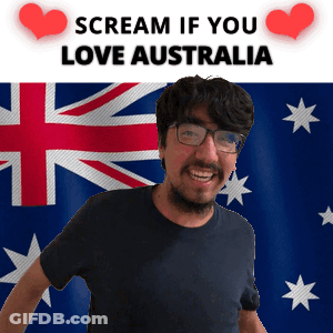A Man With Glasses Is Smiling In Front Of An Australian Flag And A Sign That Says Scream If You Love Australia GIF