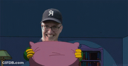 A Man With Glasses Is Smiling While Holding A Purple Pillow GIF