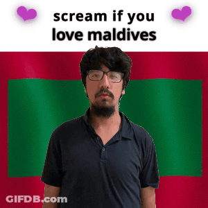 A Man With Glasses Is Standing In Front Of A Maldives Flag GIF