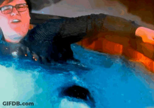 A Man With Glasses Is Swimming In A Pool Of Blue Water GIF