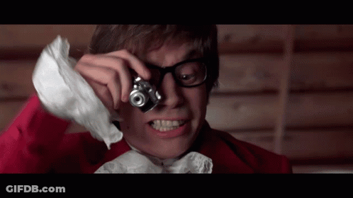 A Man With Glasses Is Taking A Picture With A Small Camera GIF