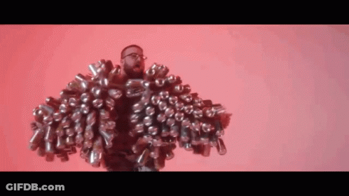 A Man With Glasses Is Wearing A Jacket Made Out Of Cans . GIF