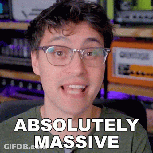 A Man With Glasses Says " Absolutely Massive " In Front Of An Orange Amplifier GIF