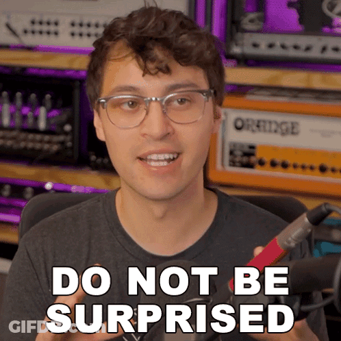 A Man With Glasses Says Do Not Be Surprised While Holding A Microphone GIF
