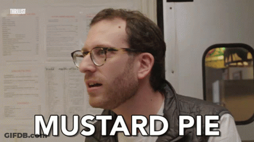 A Man With Glasses Says Mustard Pie In Front Of A Menu Board GIF