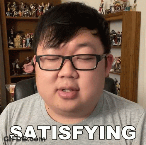 A Man With Glasses Says Satisfying In Front Of A Shelf Full Of Figurines GIF