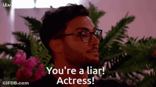 A Man With Glasses Says " You 'Re A Liar Actress " In Front Of Flowers GIF