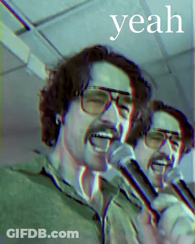A Man With Glasses Singing Into A Microphone With The Word Yeah Behind Him GIF