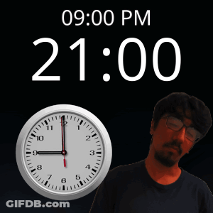 A Man With Glasses Stands In Front Of A Clock That Reads 21:00 GIF