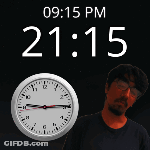 A Man With Glasses Stands In Front Of A Clock That Says 09 15 Pm GIF