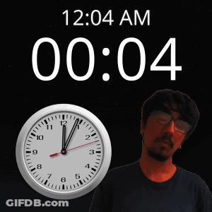 A Man With Glasses Stands In Front Of A Clock That Says 12 04 Am GIF