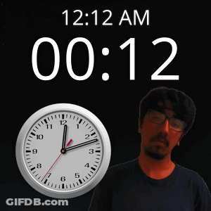 A Man With Glasses Stands In Front Of A Clock That Says 12:12 Am GIF
