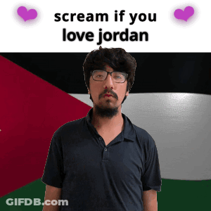 A Man With Glasses Stands In Front Of A Flag With The Words " Scream If You Love Jordan " Above Him GIF