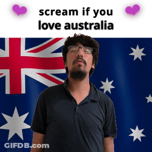 A Man With Glasses Stands In Front Of An Australian Flag GIF