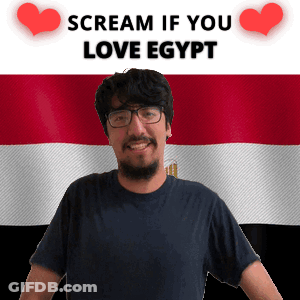 A Man With Glasses Stands In Front Of An Egyptian Flag And A Sign That Says Scream If You Love Egypt GIF