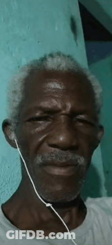 A Man With Gray Hair And A Beard Wearing Earbuds GIF