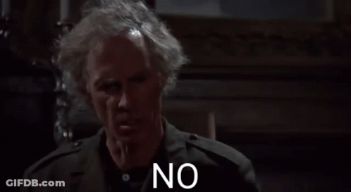 A Man With Gray Hair And A Black Jacket Is Standing In A Dark Room And Saying No . GIF