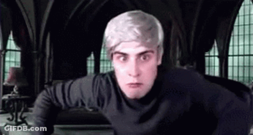 A Man With Gray Hair And A Black Shirt Is Standing In A Room With Arched Windows . GIF