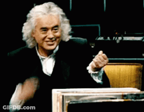 A Man With Gray Hair And A Black Suit Is Smiling And Clapping His Hands GIF