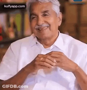 A Man With Gray Hair And A Mustache Is Smiling And Talking To Someone While Wearing A White Shirt And Tie . GIF