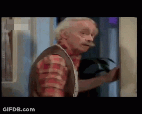 A Man With Gray Hair And A Mustache Is Standing In A Room . GIF