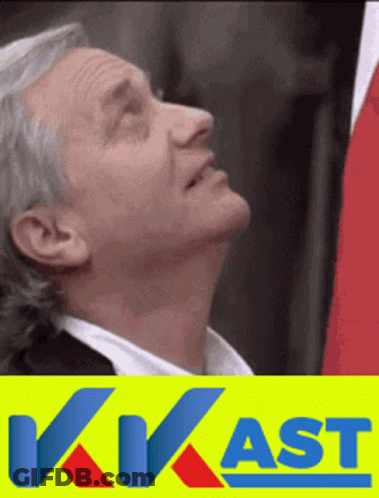 A Man With Gray Hair Is Looking Up In Front Of A Sign That Says Kwast GIF