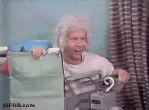 A Man With Gray Hair Is Sitting In A Chair Holding A Green Bag . GIF