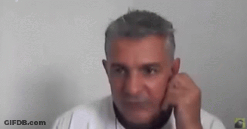 A Man With Gray Hair Is Talking On A Cell Phone While Holding His Hand To His Ear . GIF