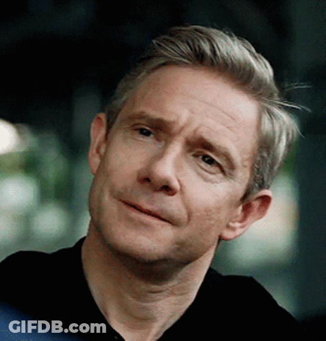 A Man With Gray Hair Is Wearing A Black Shirt And Smiling GIF
